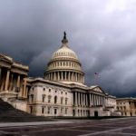 A dark, cloudy sky looms over the US Capitol building. By gelangelan/stock.adobe.com