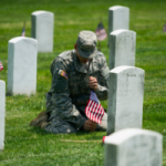 Army Pvt. II Dylan Conway, 19, of Mason, Mich., of the 3rd U.S. Infantry Regiment, also known as The Old Guard, places flags at grave sites at Arlington National Cemetery in Arlington, Va., Thursday, May 22, 2014, as part of the annual "Flags-In" ceremony in preparation for Memorial Day. (AP Photo/Cliff Owen)